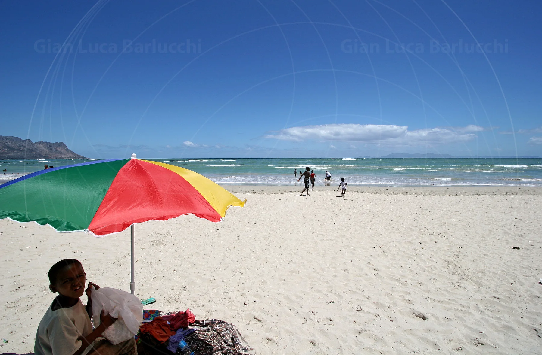 Colourful beach umbrella beside the sea and pale sand at Gordon’s Bay