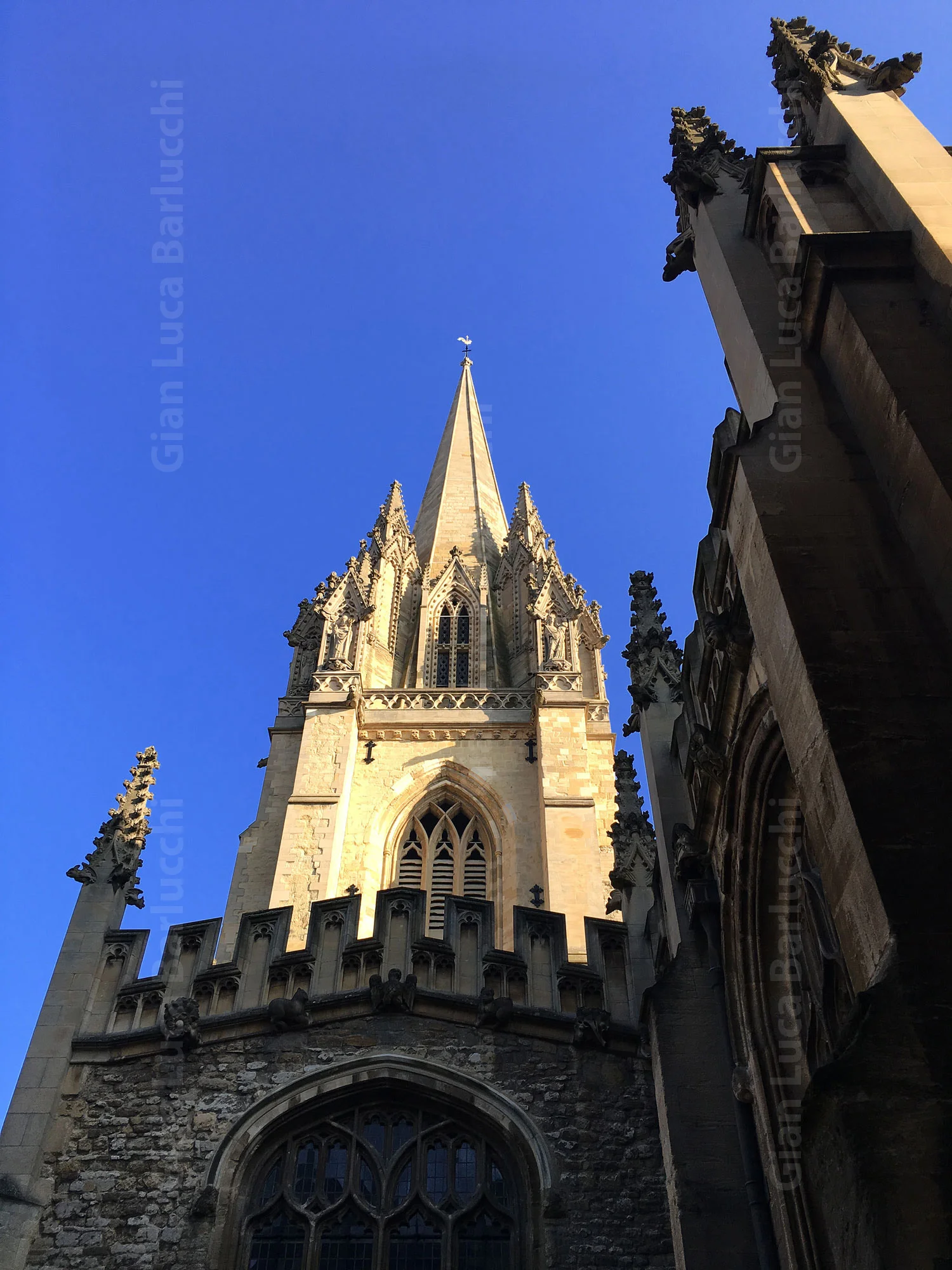 Gothic church tower rising above a London street under a blue sky