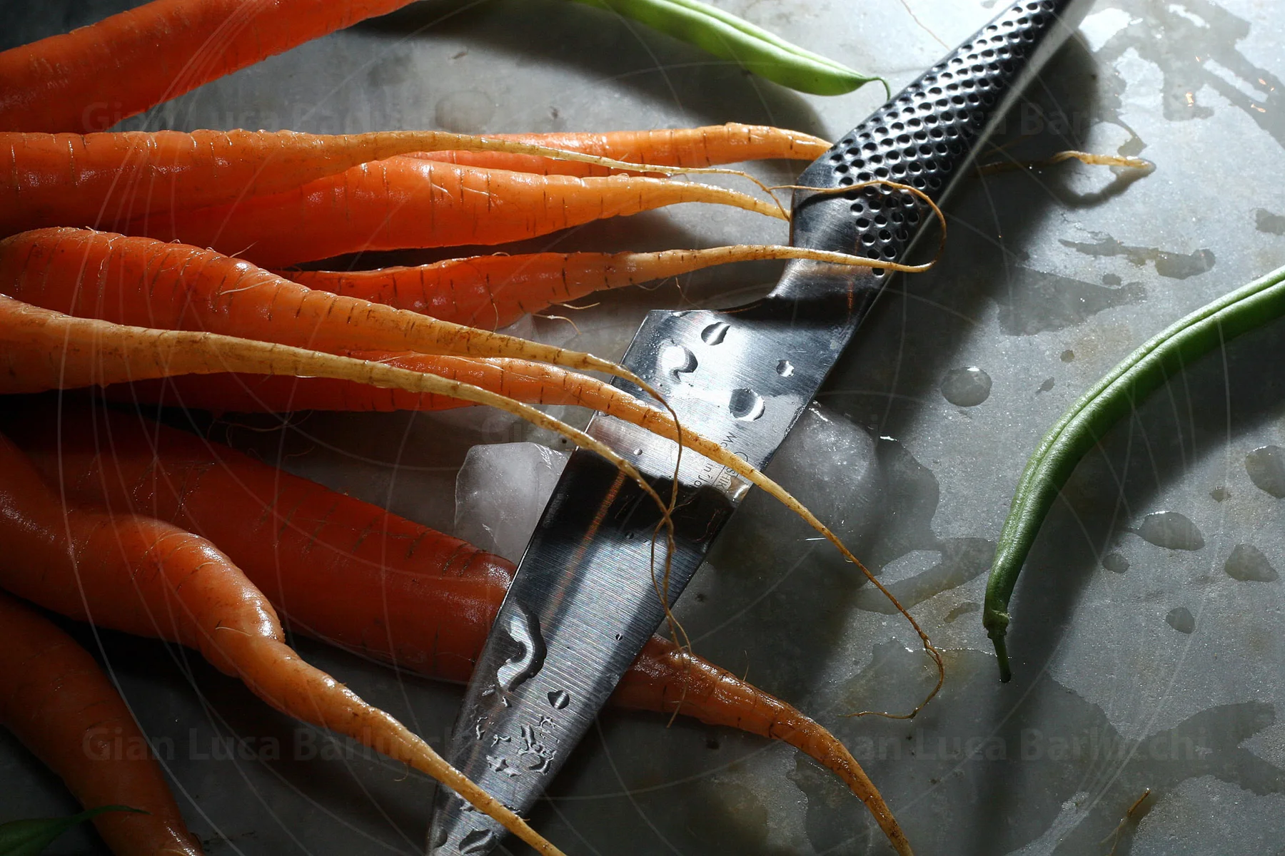 Fresh carrots and a kitchen knife on a wet chopping board