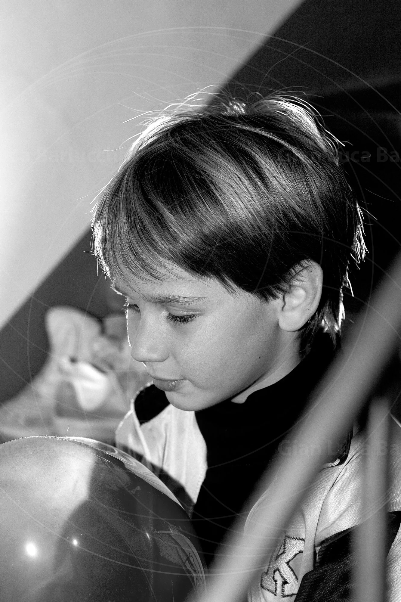 Black-and-white photograph of a child with a balloon, framed by stair rails
