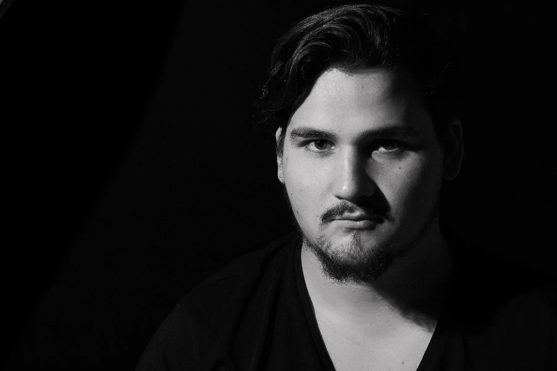 Black-and-white portrait of a young man facing the camera against a dark background