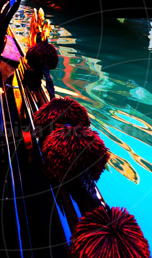 Colourful reflections beside the decorated seating of a gondola in Venice