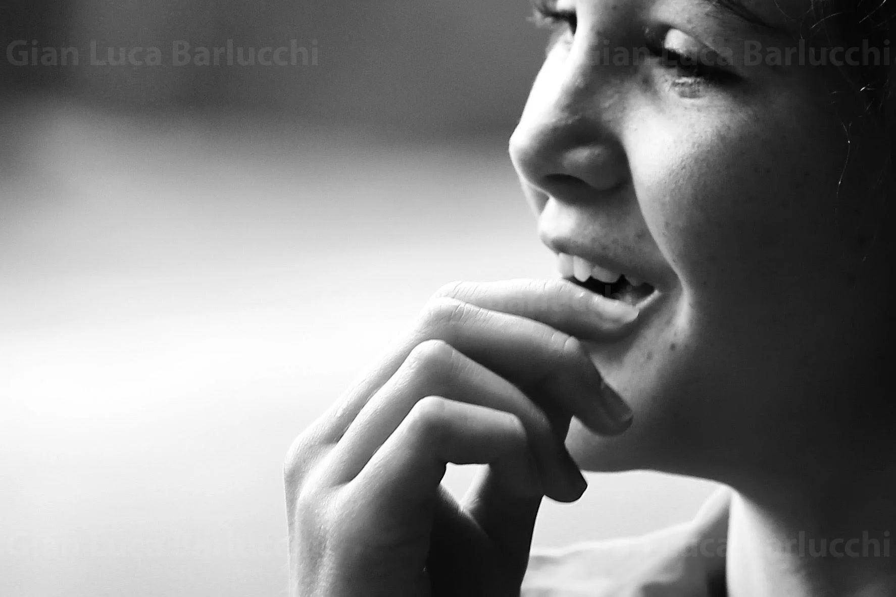 Black-and-white close-up of a child with a hand resting near their mouth