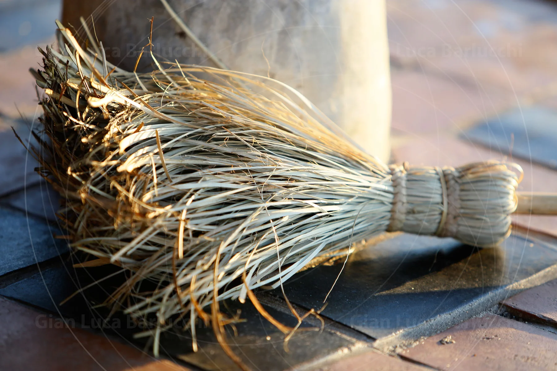 Small hand-tied straw broom resting on a wooden surface