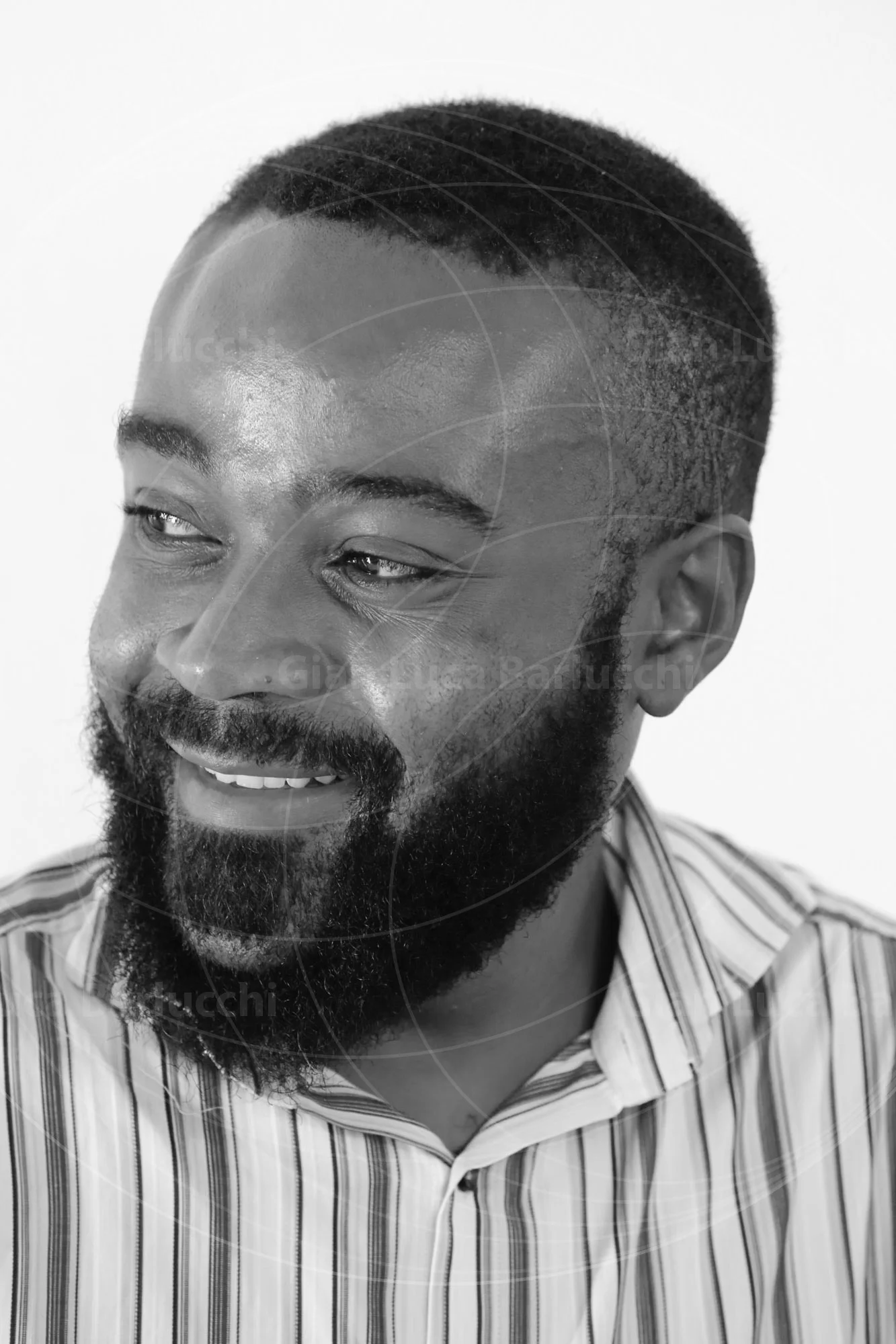 Black-and-white portrait of a smiling bearded man in a striped shirt