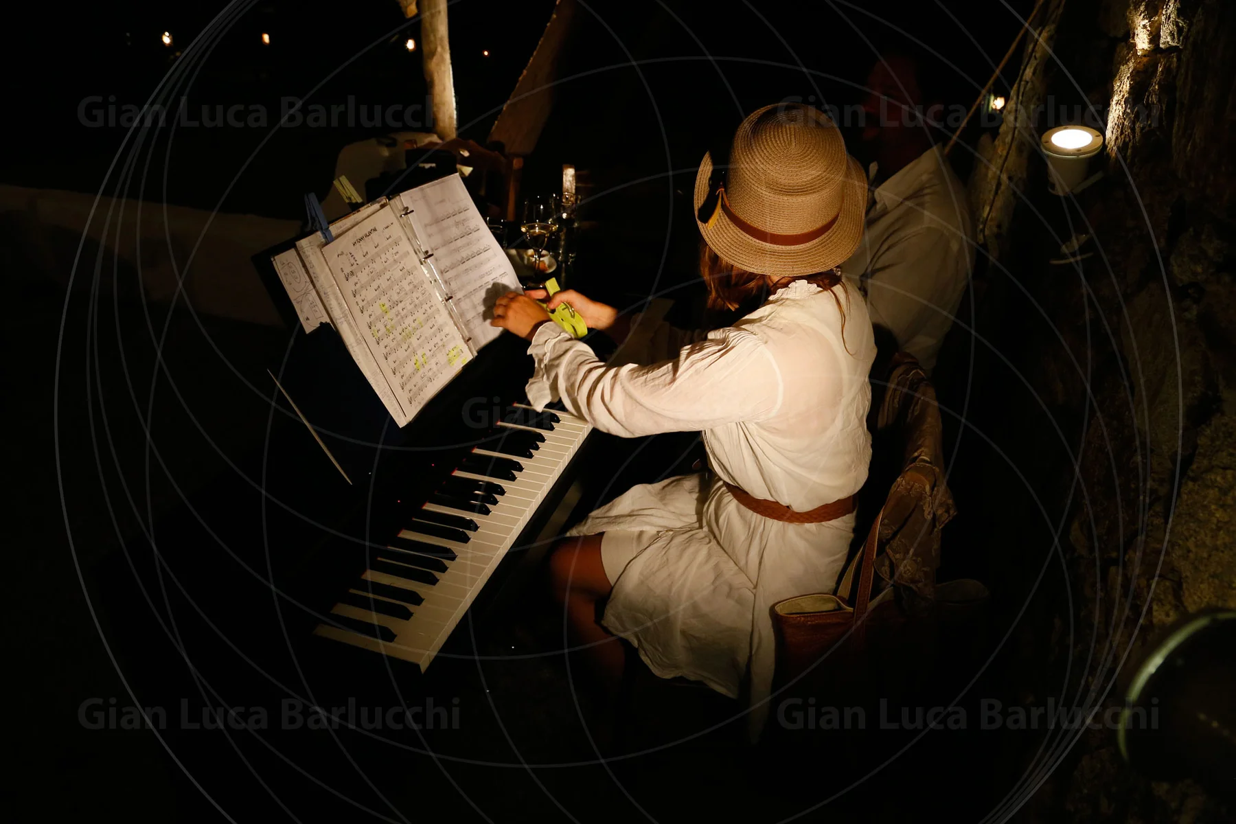 Overhead view of a musician wearing a hat at a piano with an open score