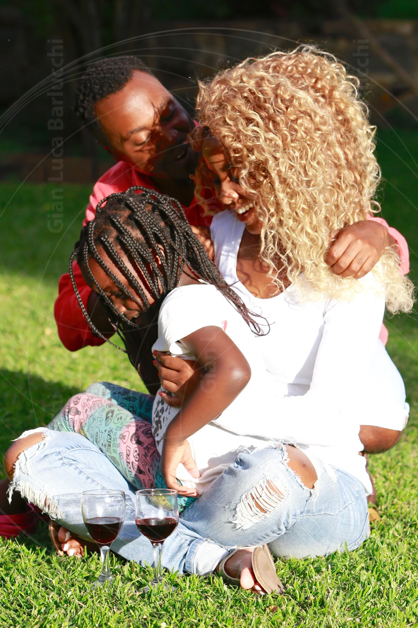 Two adults and a child sitting together on grass