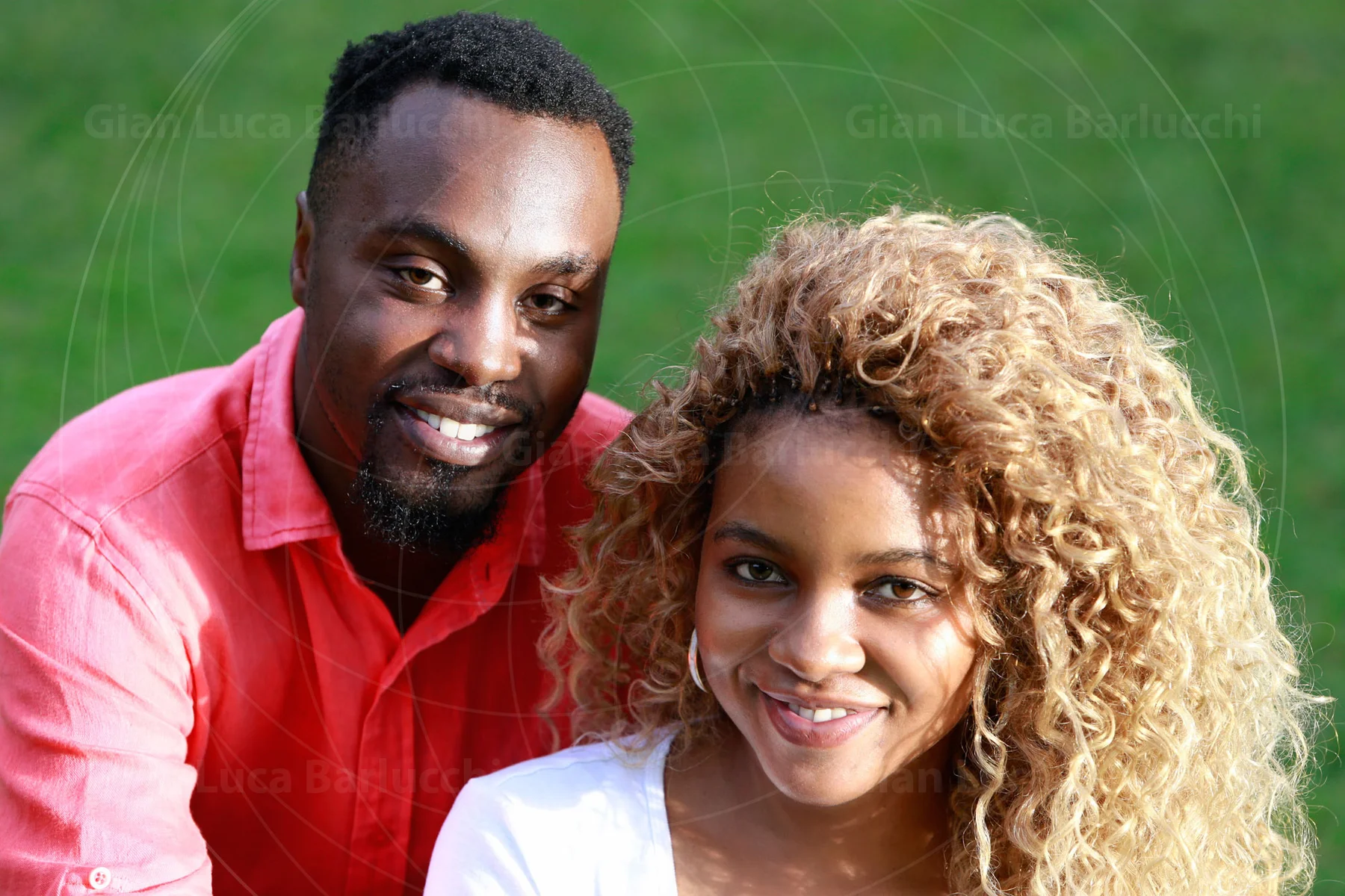 Smiling couple seated together on green grass