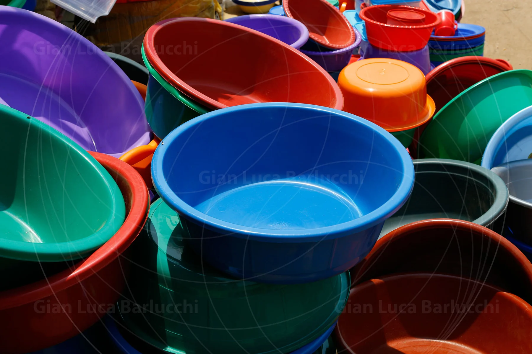 Brightly coloured plastic buckets overlapping at a market stall