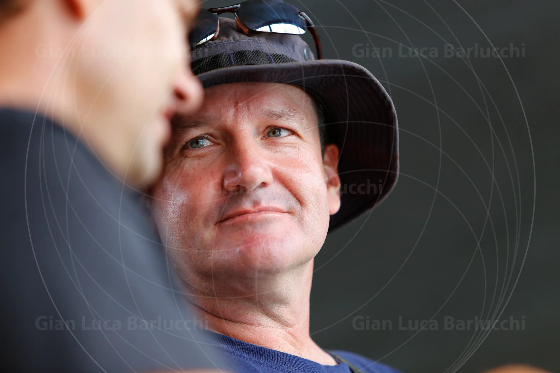 Man wearing a dark brimmed hat listening to someone beside him