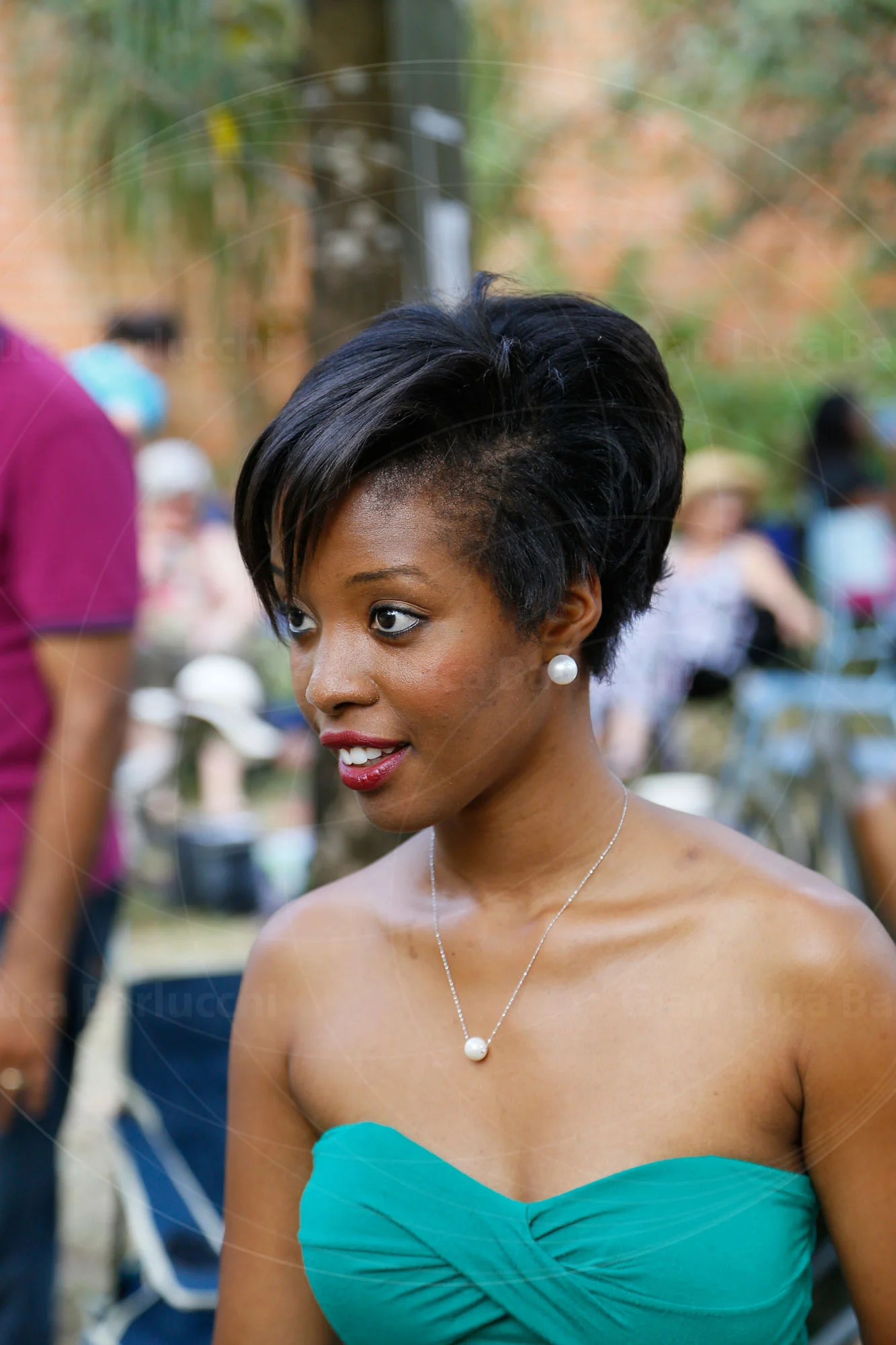 Woman in a turquoise strapless top looking to the side outdoors