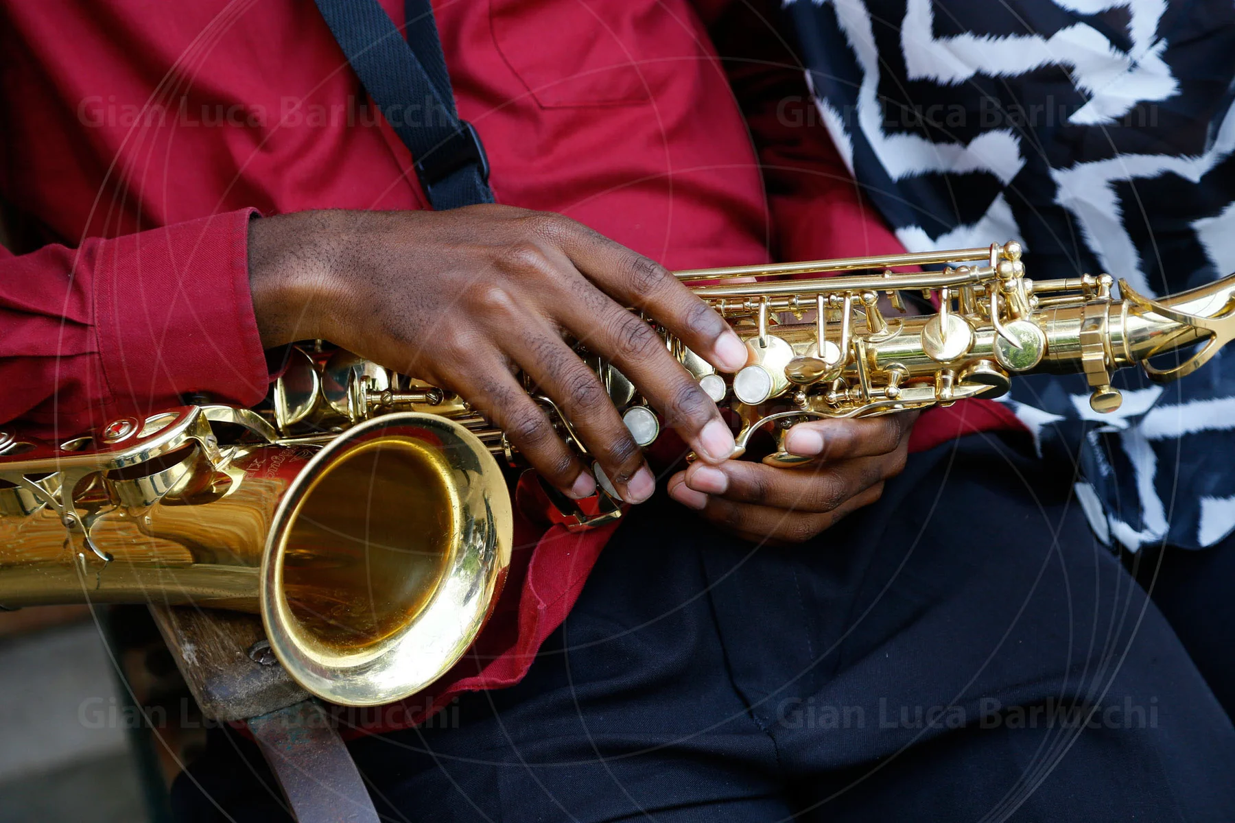 Hands resting on a golden saxophone across a musician’s lap