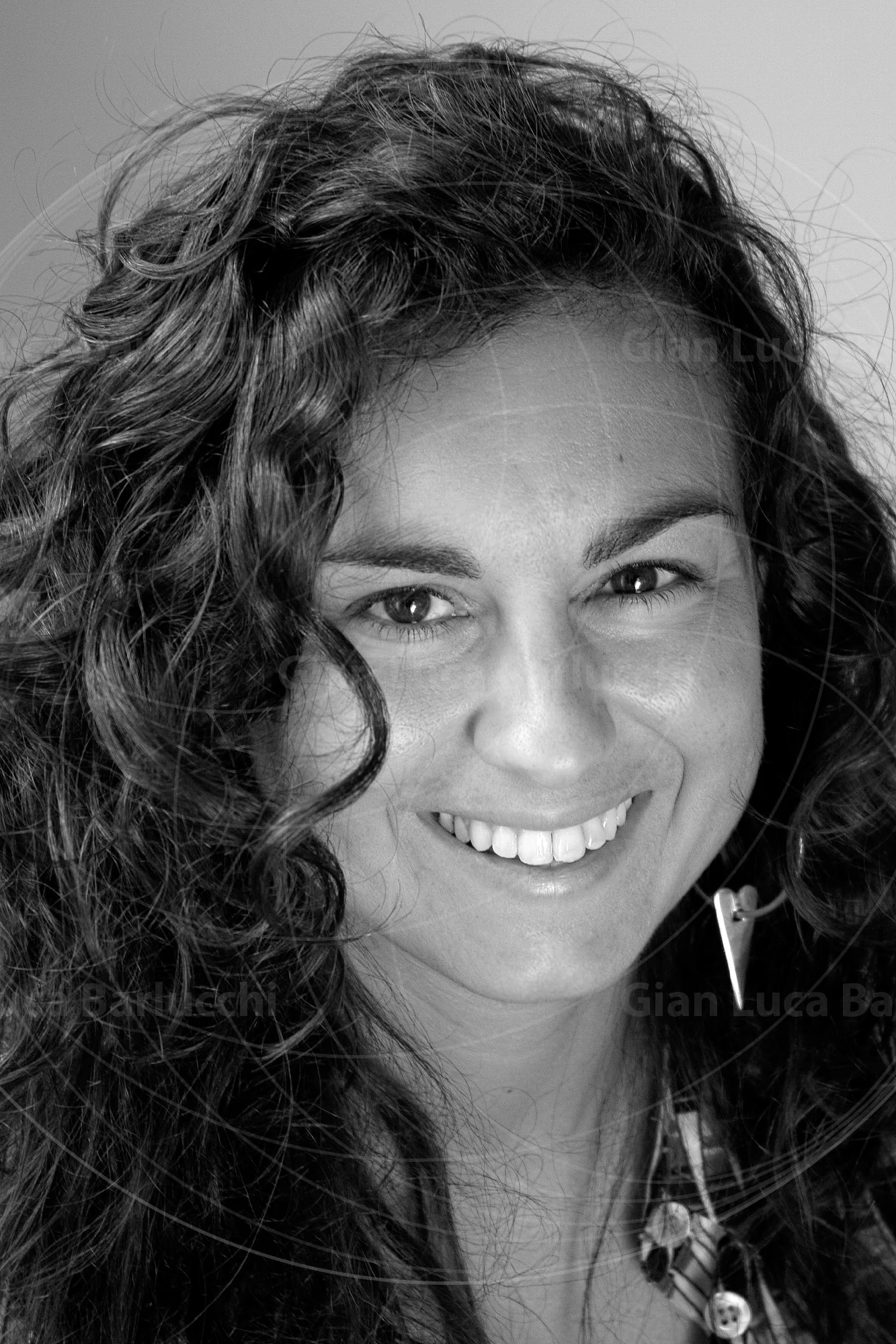 Black-and-white portrait of a smiling woman with curly hair